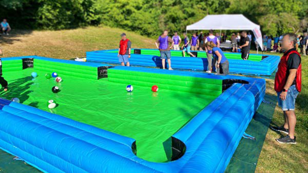 Team spielt Fußball-Billard auf aufblasbarem Spielfeld bei einem Outdoor-Firmenevent